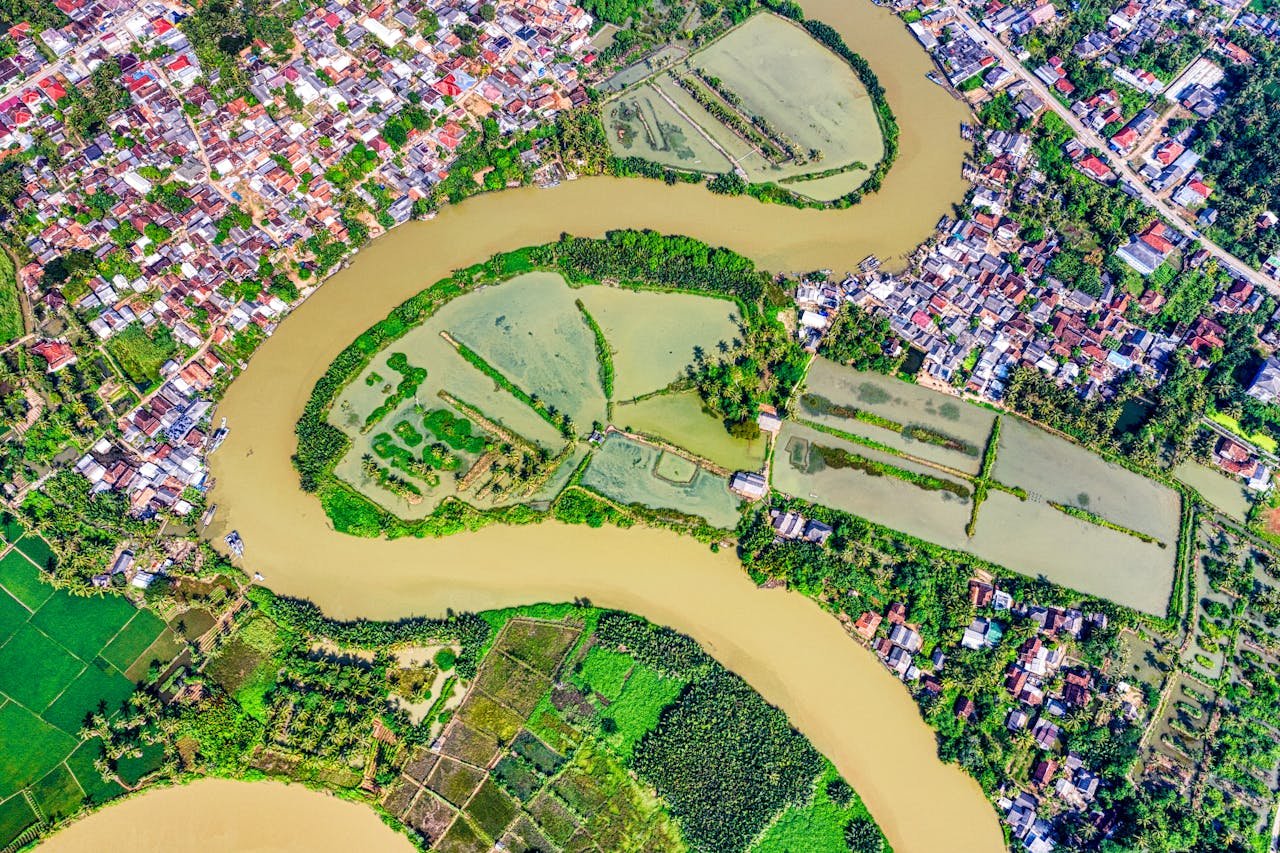 Vibrant aerial view of a river bending through lush farmland and a rural town.