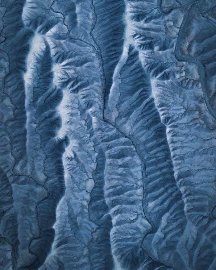 Stunning aerial shot of winter mountains showcasing icy ridges and patterns.
