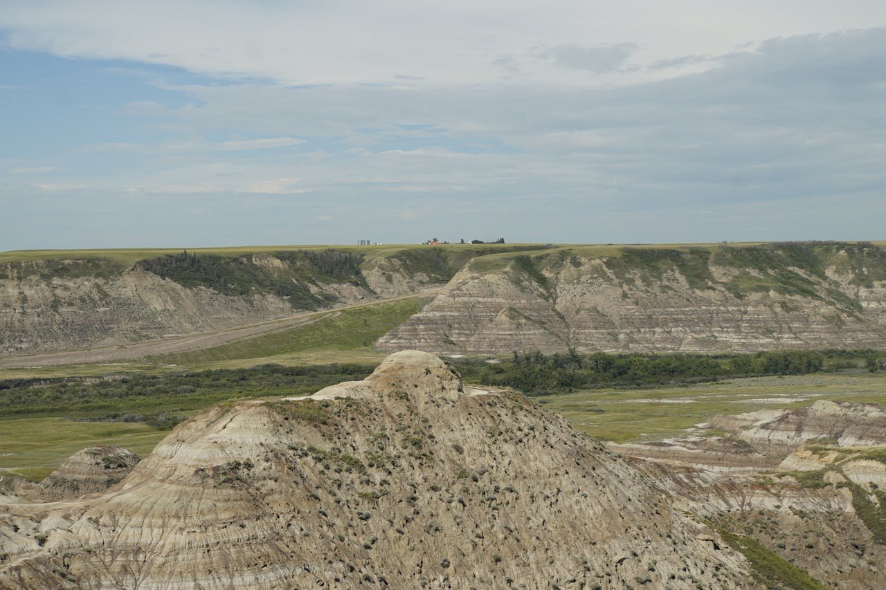 Explore the stunning rock formations and natural beauty of the Alberta Badlands under a clear daytime sky.